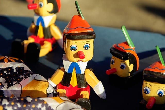 Dřevěné figurky Pinocchia s dlouhými nosy a červenými čepicemi