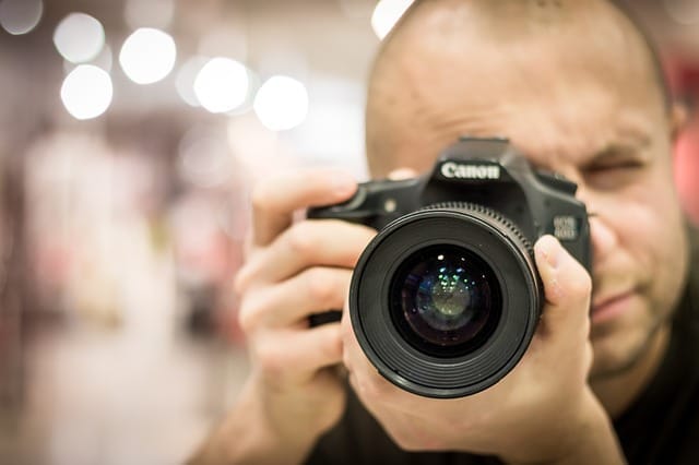 Muž míří objektivem zrcadlovky Canon přímo do fotoaparátu