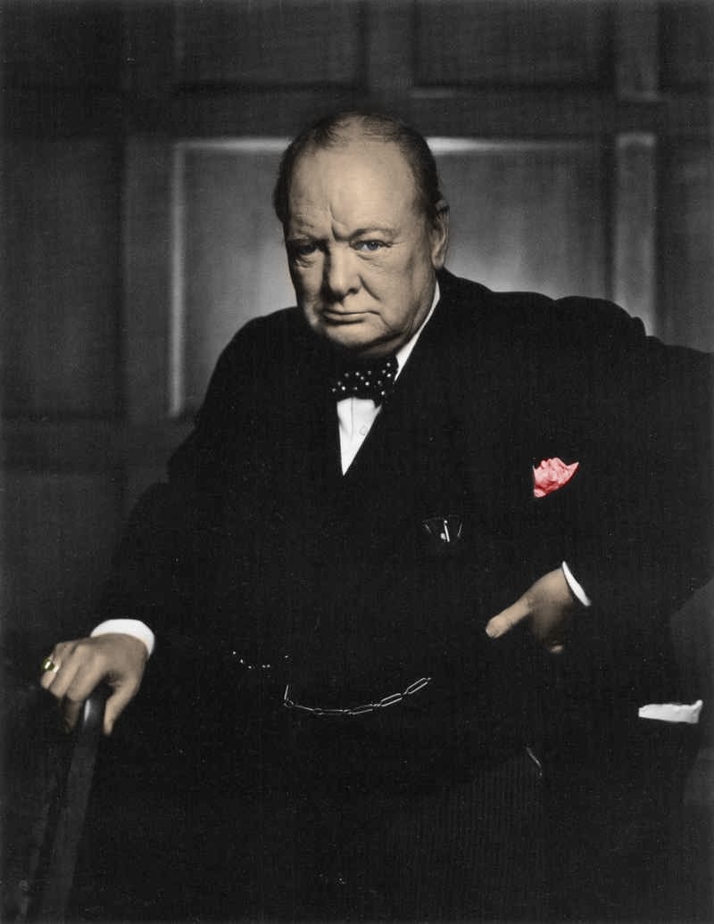 Winston Churchill v černém obleku s puntíkatým motýlkem, ruku opřenou o opěradlo židle, s červenou růží v kapse saka na kolorovaném portrétu