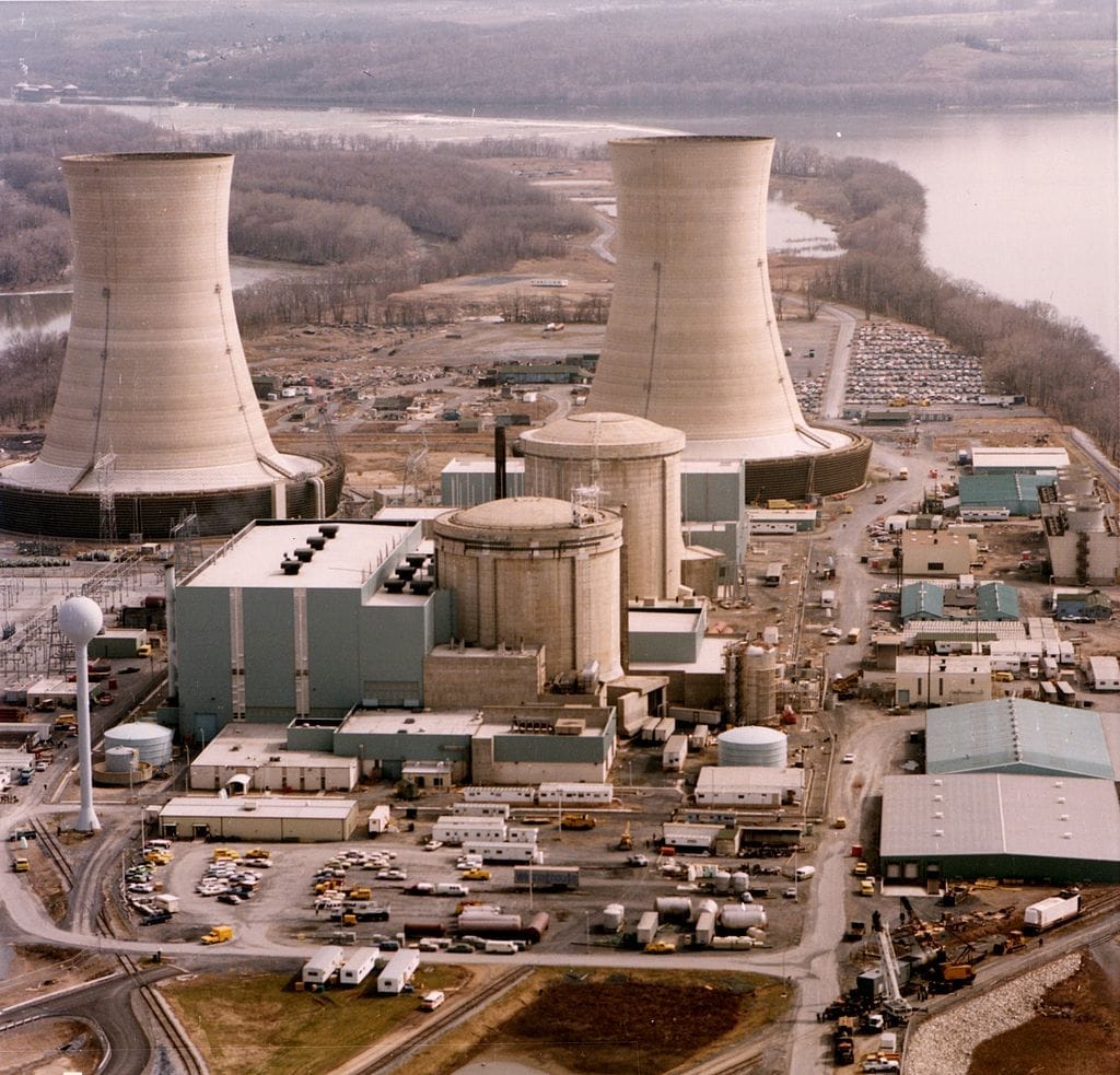 Letecký pohled na jadernou elektrárnu Three Mile Island se dvěma chladicími věžemi, kupolí reaktoru a areálem u řeky