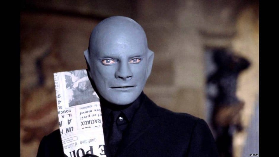 Fantomas s modrošedou holou maskou drží u tváře francouzské noviny