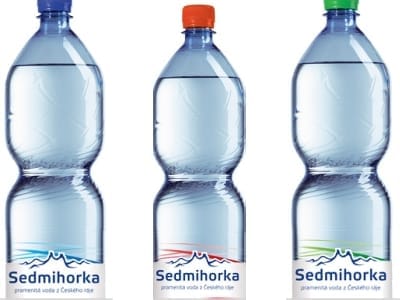 Tři plastové láhve vody Sedmihorka s modrým, červeným a zeleným uzávěrem a popiskem „pramenitá voda z Českého ráje“