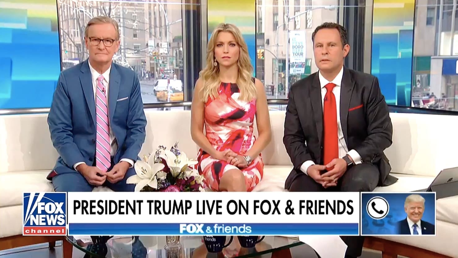 Tři moderátoři pořadu Fox and Friends na pohovce ve studiu, dole titulek „President Trump live on Fox & Friends“ a ikona telefonu s fotkou Donalda Trumpa