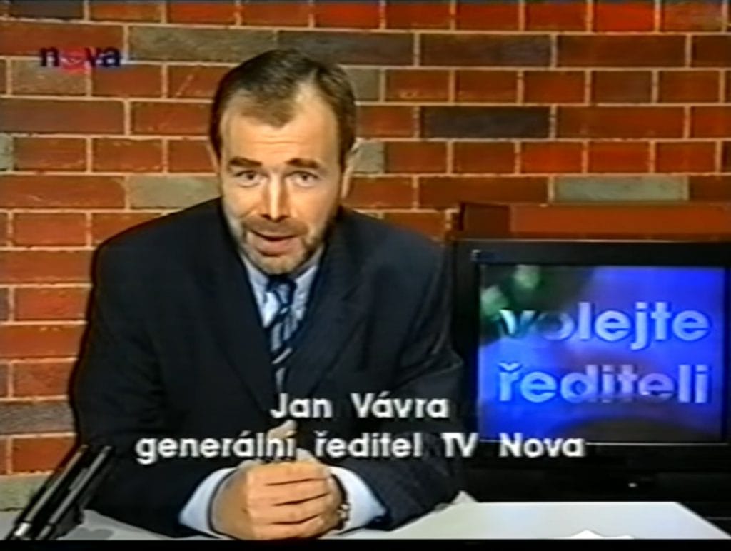 Jan Vávra sedí ve studiu před cihlovou zdí, titulek „Jan Vávra, generální ředitel TV Nova“ a monitor s nápisem „Volejte řediteli“