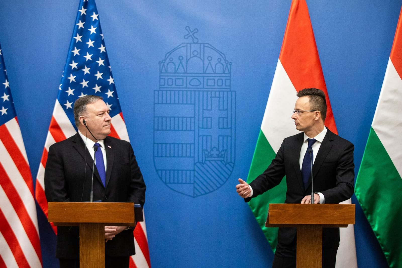Mike Pompeo a Péter Szijjártó u dvou řečnických pultů před americkými a maďarskými vlajkami a maďarským státním znakem