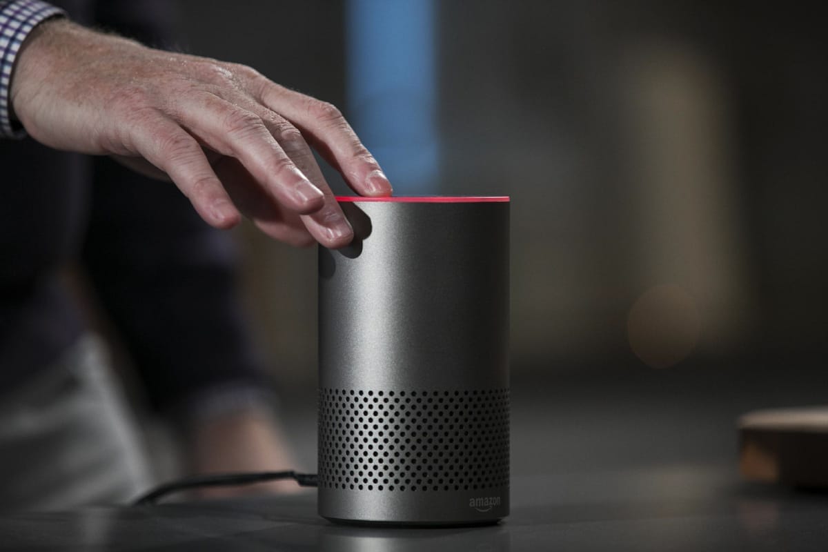 Ruka se dotýká horní části chytrého reproduktoru Amazon Echo se svítícím červeným prstencem