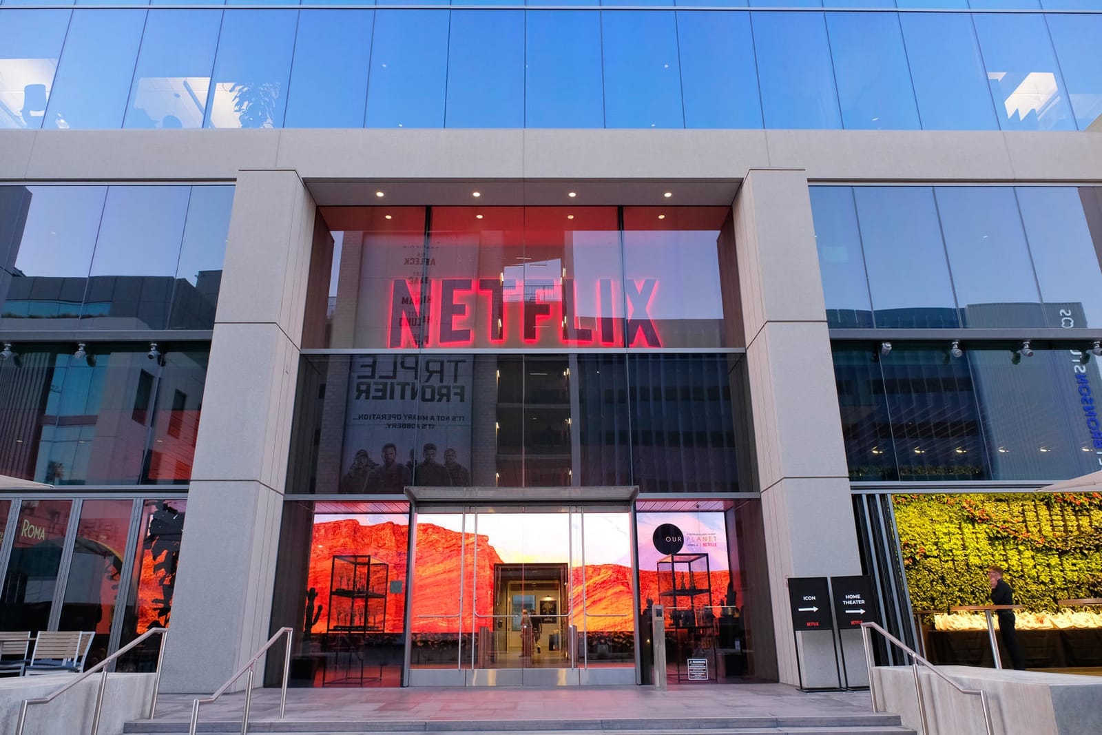 Prosklená budova s neonovým logem Netflix nad vstupem a plakátem k filmu Triple Frontier