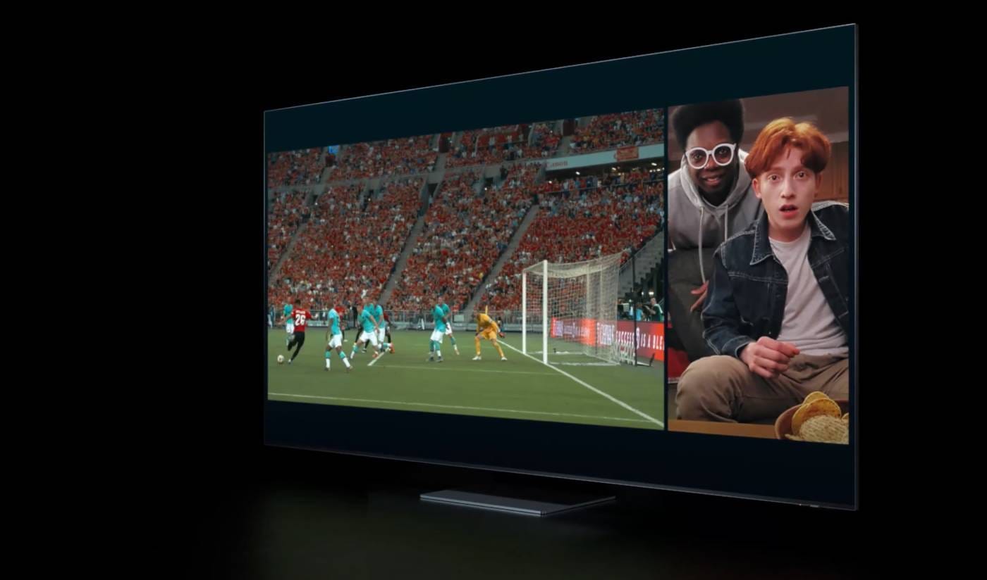Televizor s rozdělenou obrazovkou: vlevo fotbalový zápas na stadionu, vpravo dva mladíci sledující sport s bramborovými lupínky