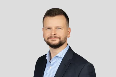 Filip Rožánek po ramena na světle šedém pozadí, v tmavě modrém saku a světle modré košili