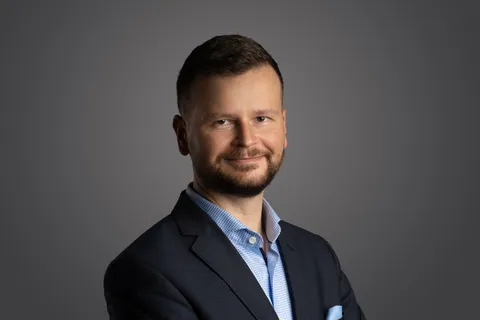 Filip Rožánek po ramena na tmavě šedém pozadí, v saku s náprsním kapesníčkem